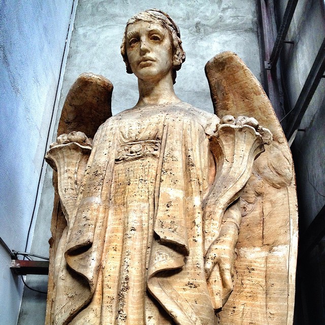 A weathered statue of a youthful angel with dark eyes and a wistful expression.