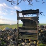 Abandoned hunting outlook with green fields in the background.