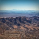 View from a plane of dense suburbs against a mountain range, with empty desert beyond.