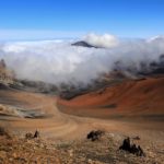 The surreal landscape of Haleakalā crater, swirled in clouds and streaks of red volcanic tufa rock.