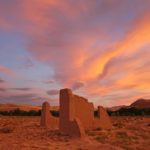 Desert ruins and a colorful sunset sky.