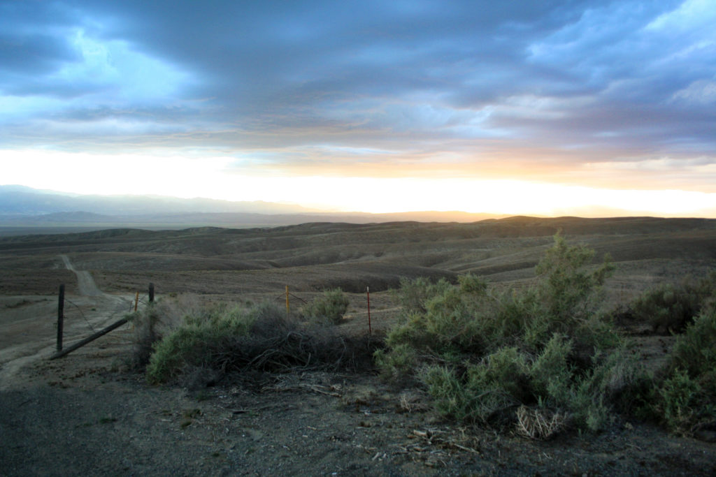 Dry open landscape in Central California with rain clouds in the distance.